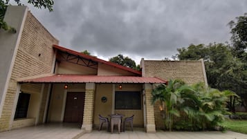 Un edificio con entrada cubierta, una puerta y un pequeño espacio al aire libre con sillas.