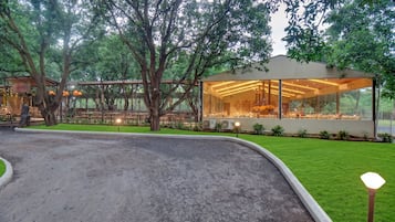 Un edificio moderno con amplios ventanales, rodeado de abundante vegetación y árboles.