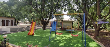 A playground with a slide, swings, and a swing set.