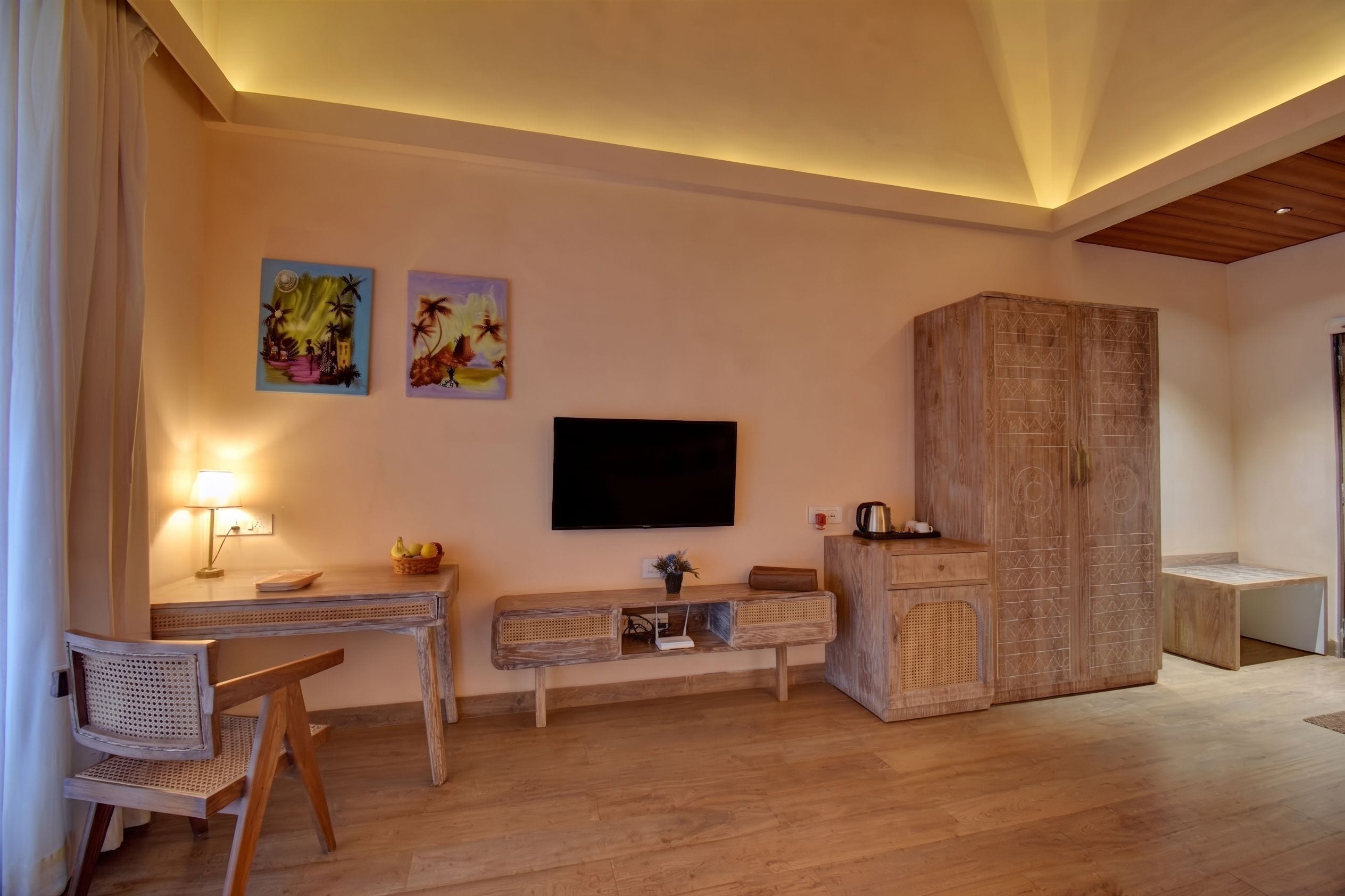 Een hotelkamer met een houten bureau, een aan de muur bevestigde televisie en een grote houten kast.
