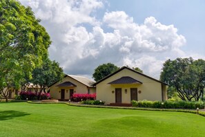 Two single-story buildings with a flat roof, surrounded by well-maintained lawns and trees. - Tiki Farms – Polynesian Boutique Resort, Karjat (Karjat)