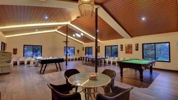A spacious indoor area with a pool table, billiards table, and a billiard cue rack.