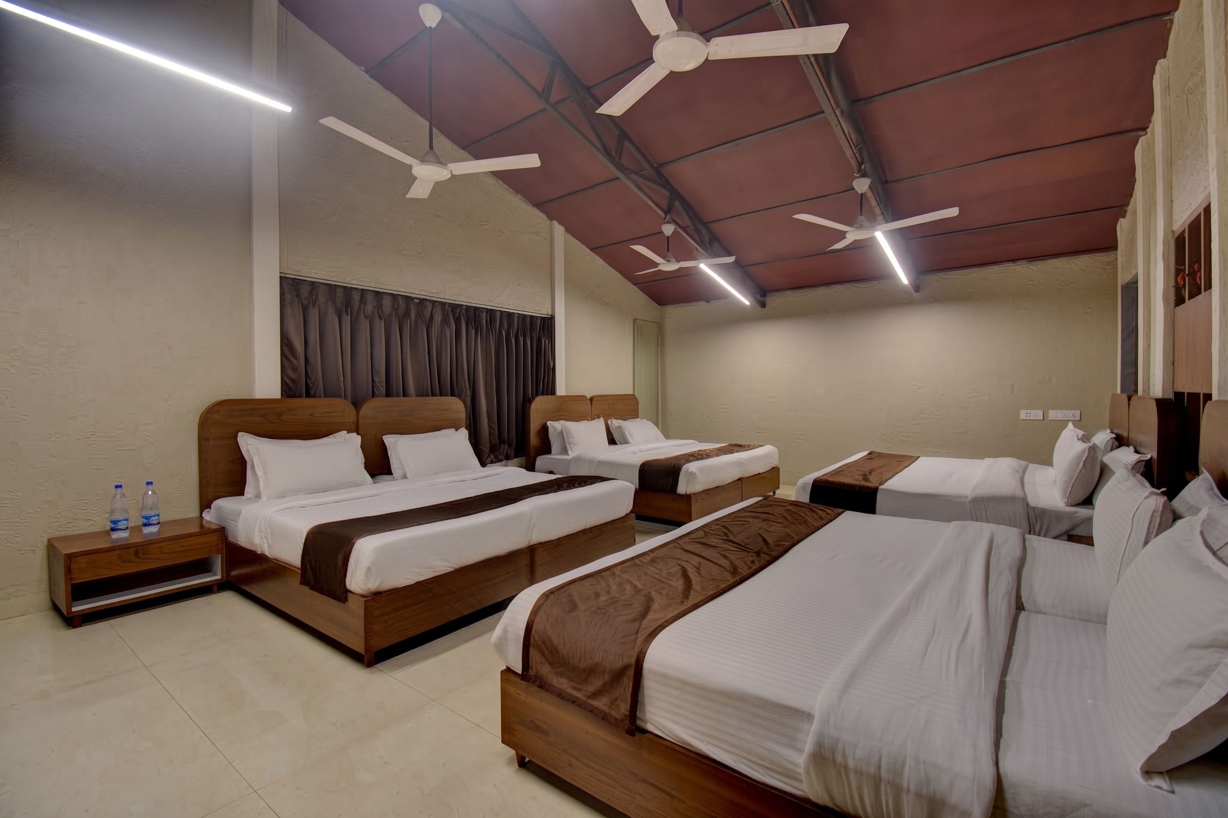 A hotel room with two beds, a wooden headboard, a nightstand, and a ceiling fan.