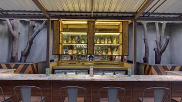 A bar area with a counter, shelves of bottles, and chairs.