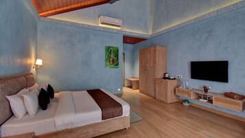 A hotel room with a bed, a desk, a wardrobe, a television, and an air conditioning unit.