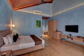 Una habitación de hotel con cama, escritorio, armario, televisor y aire acondicionado.