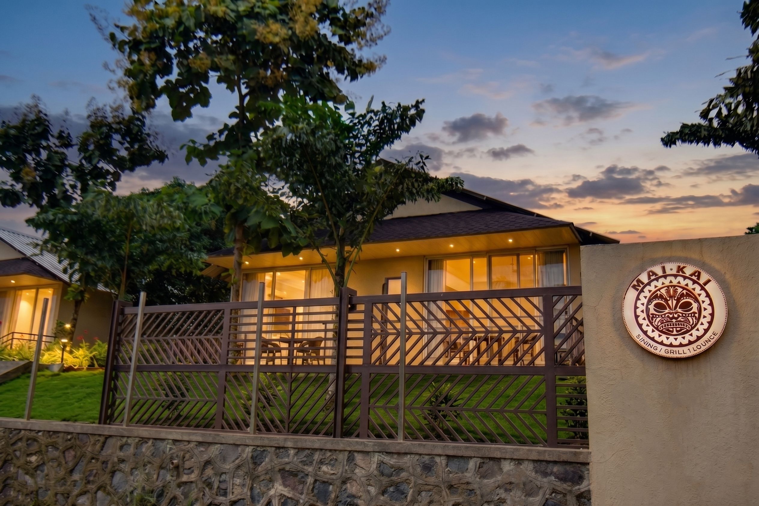 A residential property with a gated entrance, a stone wall, and a well-maintained lawn.