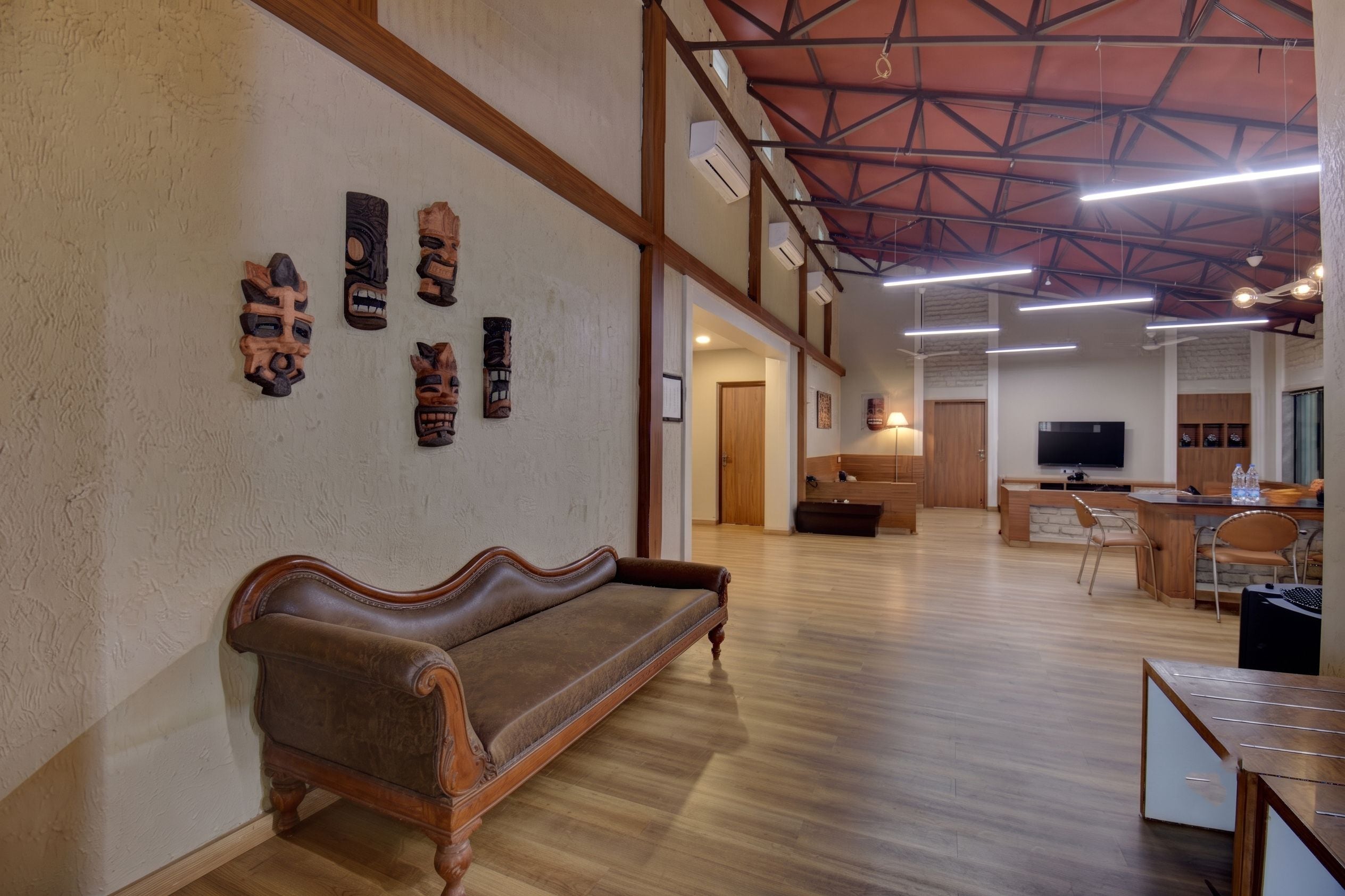 A spacious room with a wooden bench, a television, and a desk with chairs.
