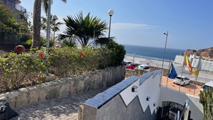 A coastal hotel with a view of the sea, a paved walkway, and a stone wall with plants. - Sunny Seaview Modern apt - Pool and Beach Access (Mogan)
