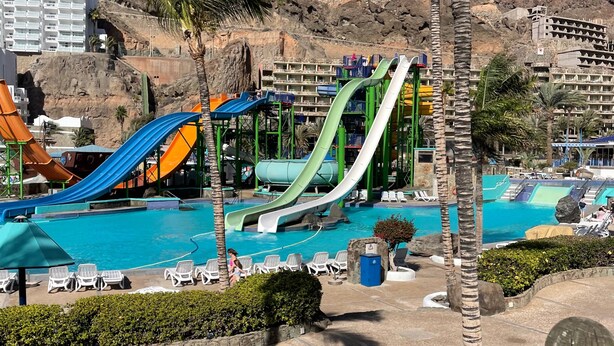 A resort with multiple water slides, a pool area, and a mountainous backdrop. - Sunny Seaview Modern apt - Pool and Beach Access (Mogan)