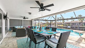 A sunlit patio with a pool, outdoor seating, and a ceiling fan. - Relaxing Retreat, Heated Pool,  Gulf Access NEW (Cape Coral)