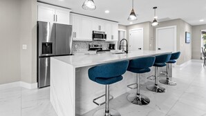 A modern kitchen with stainless steel appliances, white cabinets, and a marble countertop. - Relaxing Retreat, Heated Pool,  Gulf Access NEW (Cape Coral)