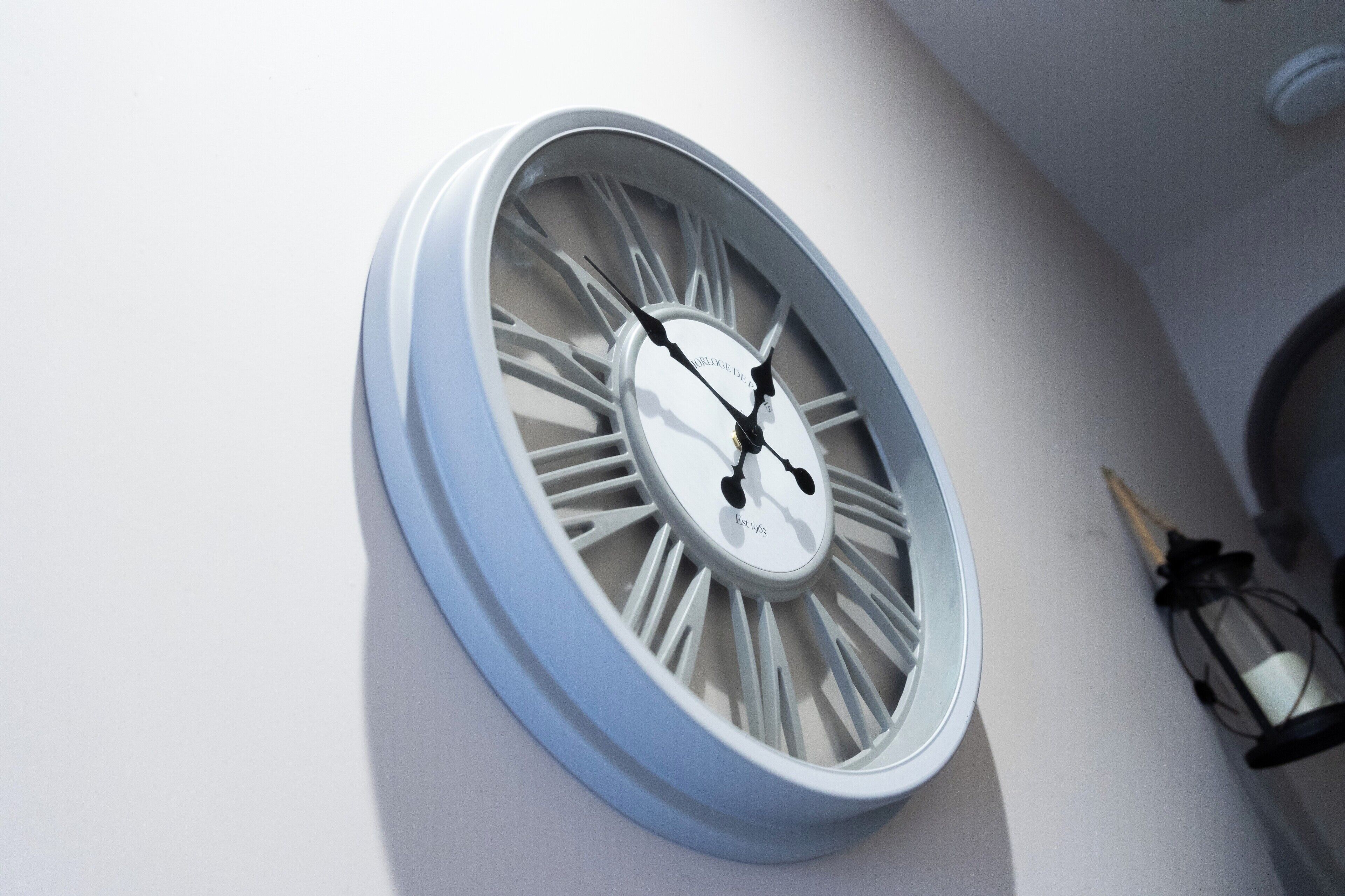 A wall-mounted clock with Roman numerals and a white face.