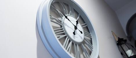 A wall-mounted clock with Roman numerals and a white face.