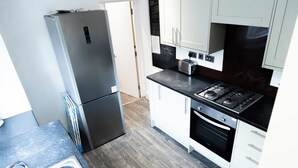 Eine moderne Küche mit Edelstahl-Kühlschrank, Gasherd und weißen Schränken.