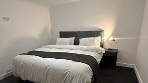 A bedroom with a bed, a nightstand, a lamp, and a ceiling light. - House-sleeps8-parking-garden (Leeds)