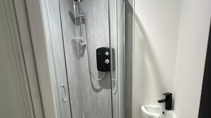 A modern bathroom with a glass-enclosed shower, a white sink, and a wooden floor. - House-sleeps8-parking-garden (Leeds)