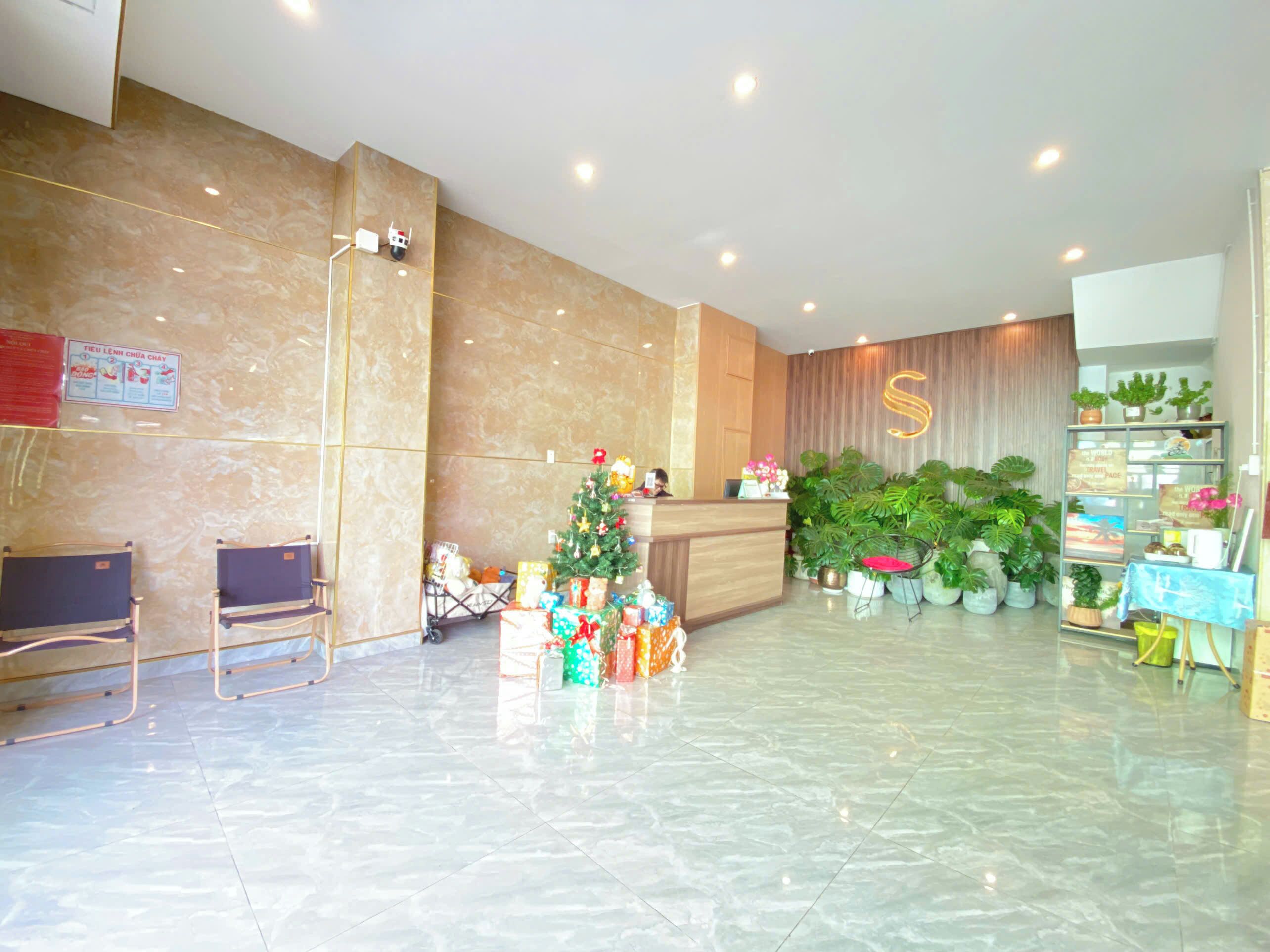 A hotel lobby with a reception desk, a Christmas tree, and a large S-shaped sign.