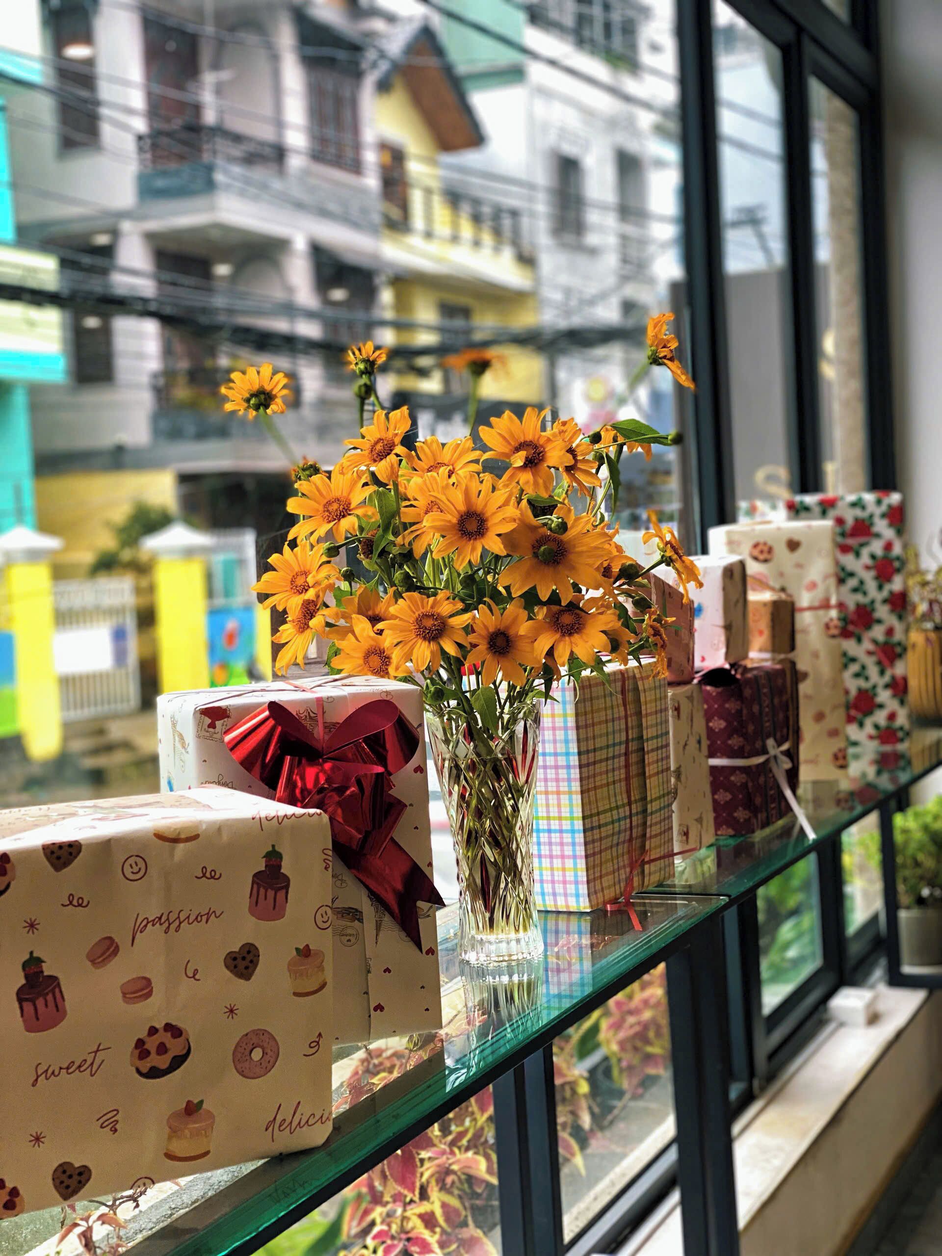 A window display with wrapped gifts and a vase of flowers.