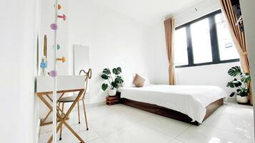 A modern bedroom with a bed, a desk, and two potted plants.