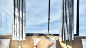 Ein Hotelzimmer mit einem großen Bett, zwei Nachttischen und einem Fenster mit Vorhängen.