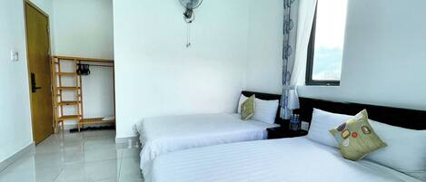 A hotel room with two beds, a wooden ladder, a ceiling fan, and a window with curtains.