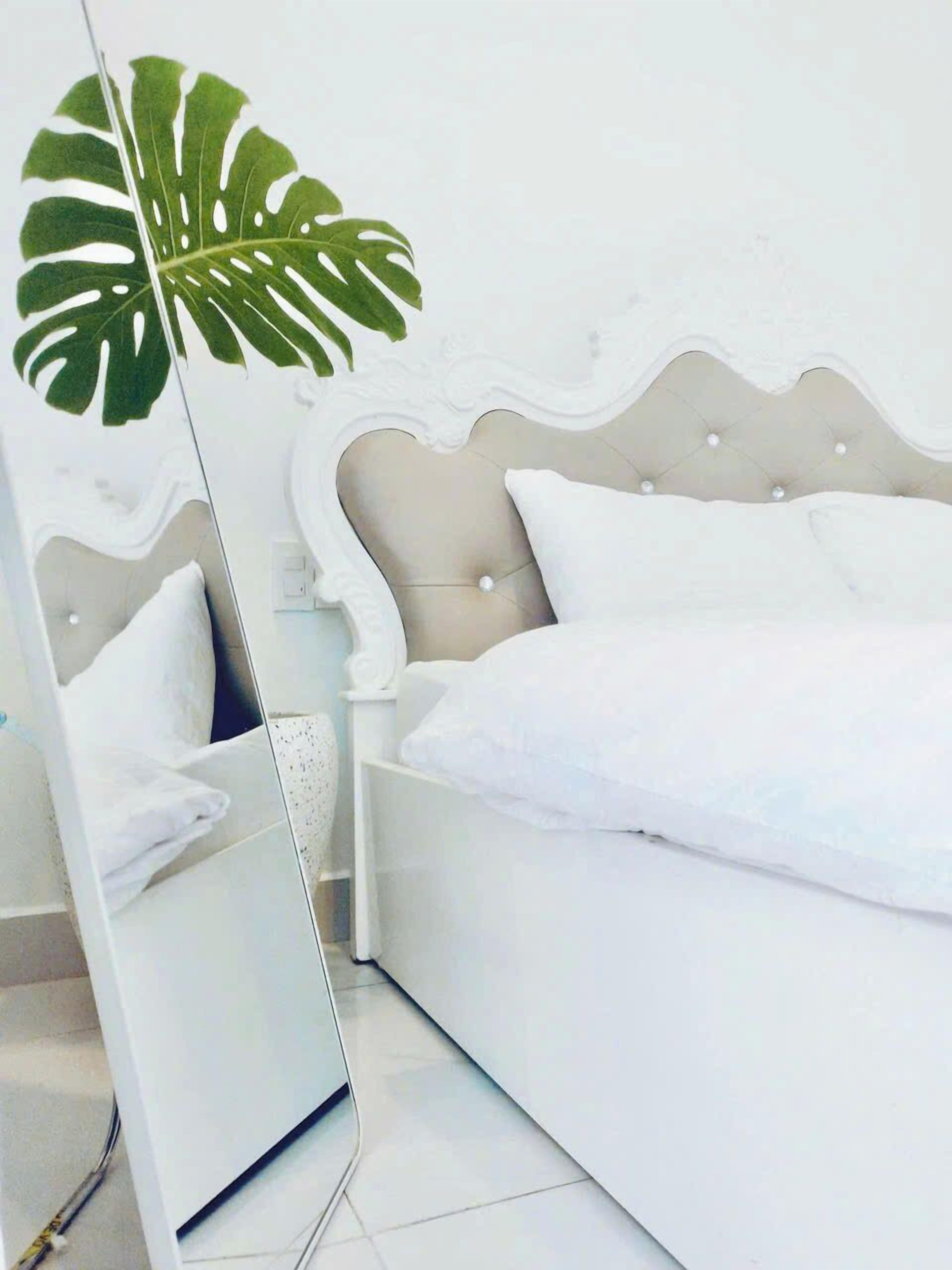 A modern bedroom with a bed, a nightstand, and a mirror.