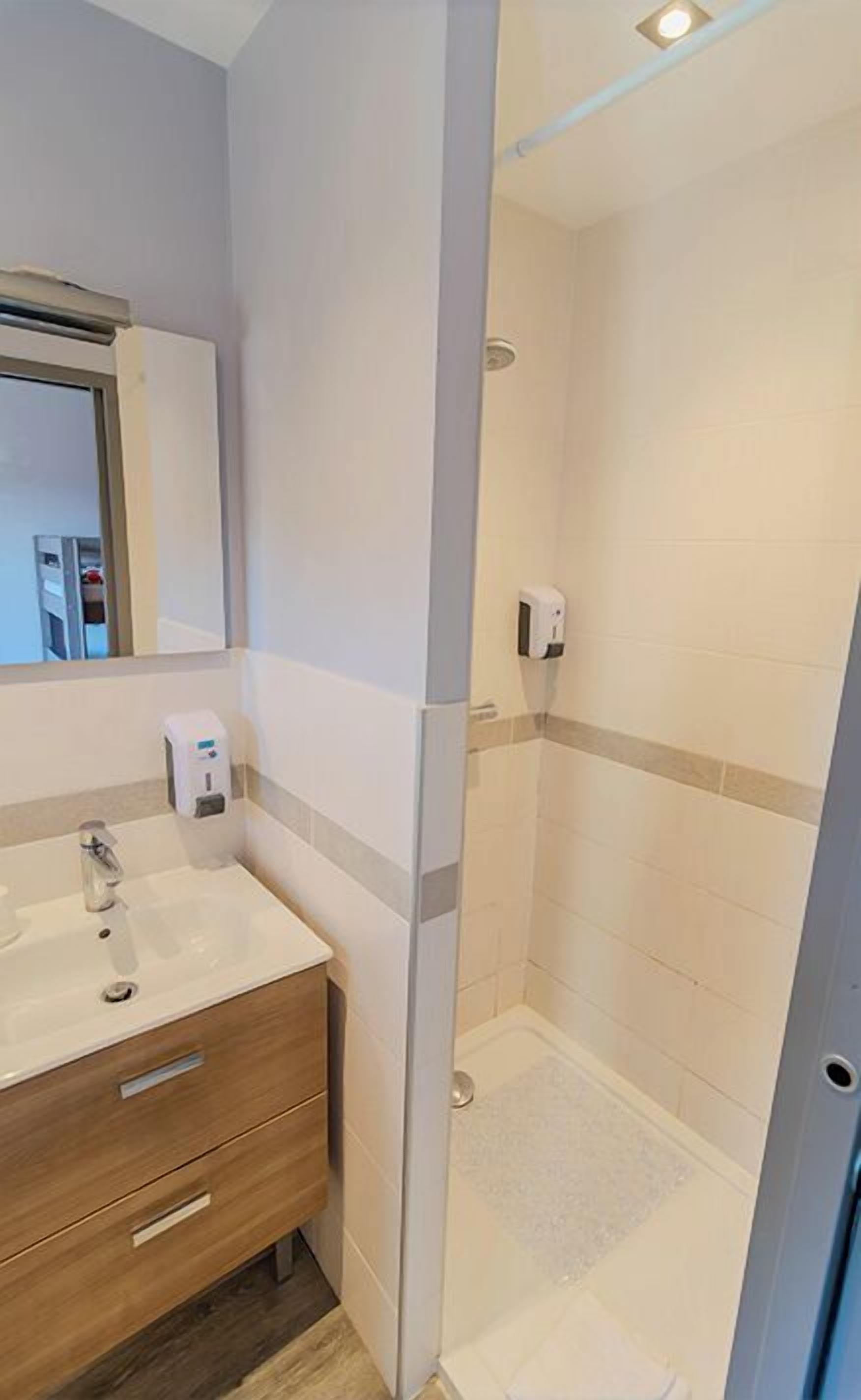 Une salle de bain moderne avec une douche à parois de verre, un lavabo blanc et un meuble-lavabo en bois.