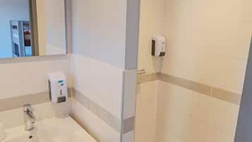 Une salle de bain moderne avec une douche à parois de verre, un lavabo blanc et un meuble-lavabo en bois.
