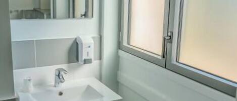 A modern bathroom with a white sink, mirror, and green radiator.