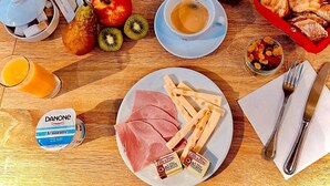 A breakfast table with a magazine, coffee, fruit, pastries, and cheese. - Hôtel de l'Abbaye  (Cluny)