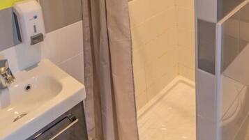 A bathroom with a shower, a sink, and a mirror.