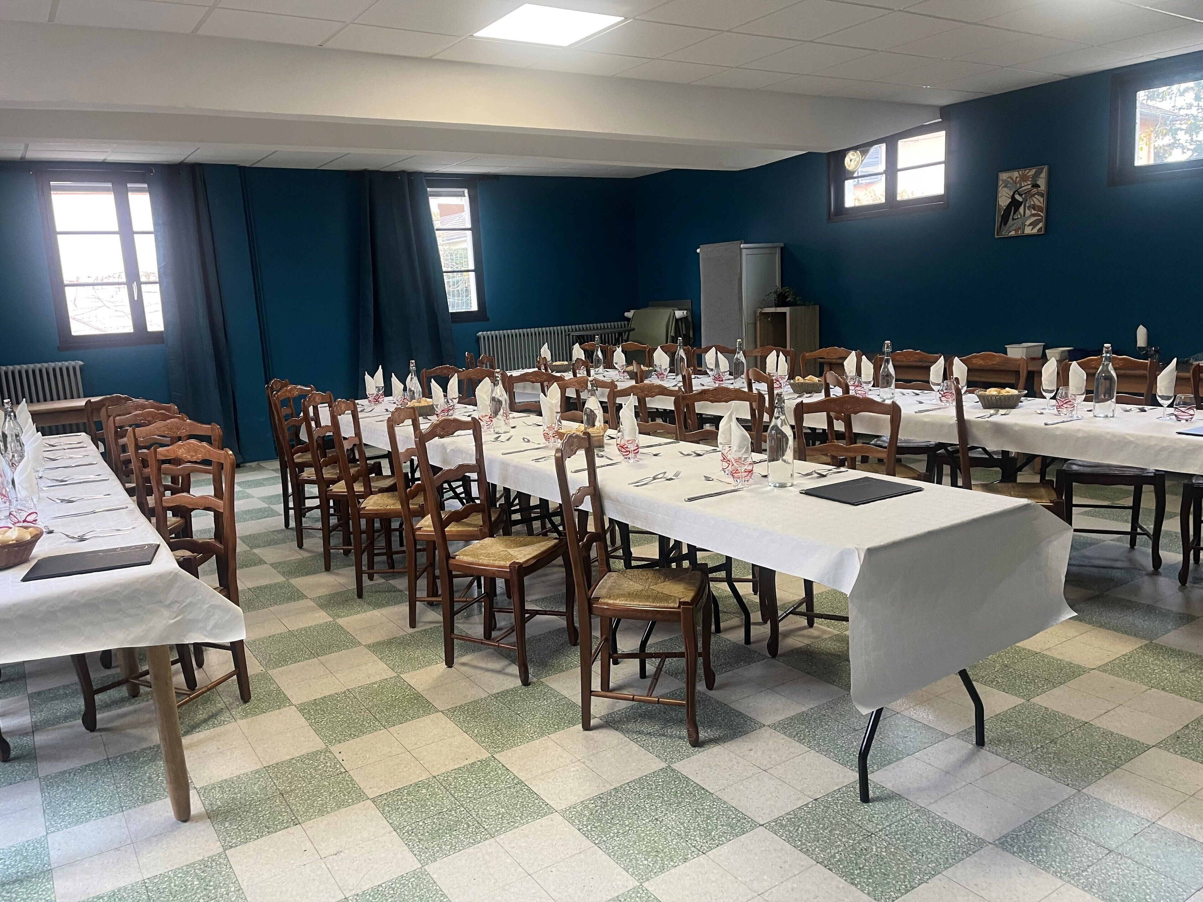 A conference room with multiple tables set for a meeting, equipped with chairs, tables, and various items like bottles and plates.