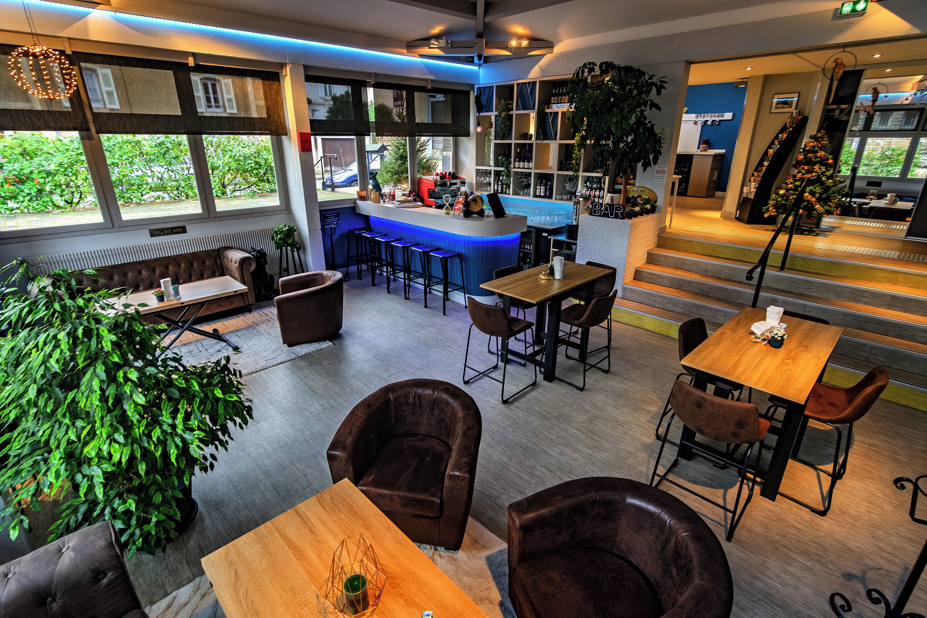 Een moderne bar met een toonbank, krukken en een groot raam met uitzicht op groen.