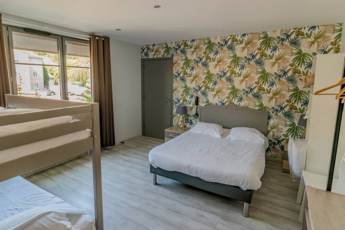 Een hotelkamer met een bed, een bureau, een stoel, een kledingkast en een raam met gordijnen.