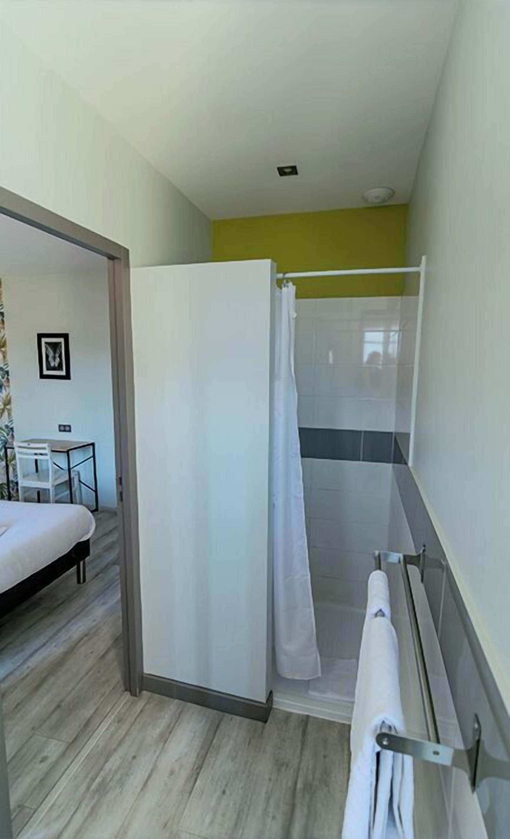 A modern bathroom with a shower, toilet, and a small table with a chair.