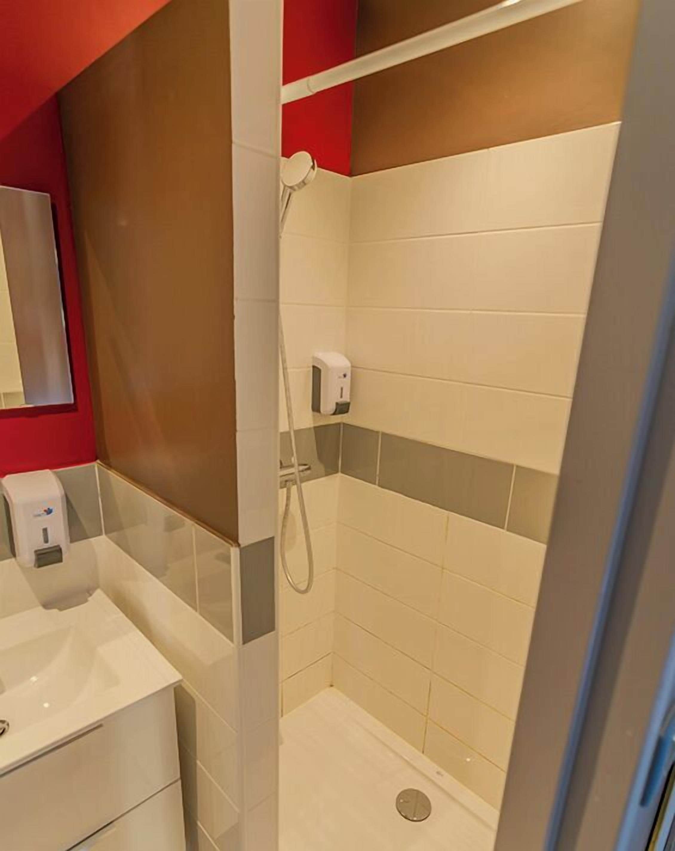 Une salle de bain avec une douche, un lavabo et un miroir.