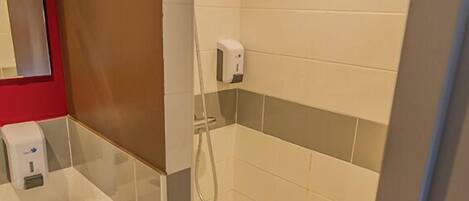 Un baño con ducha, lavamanos y espejo.
