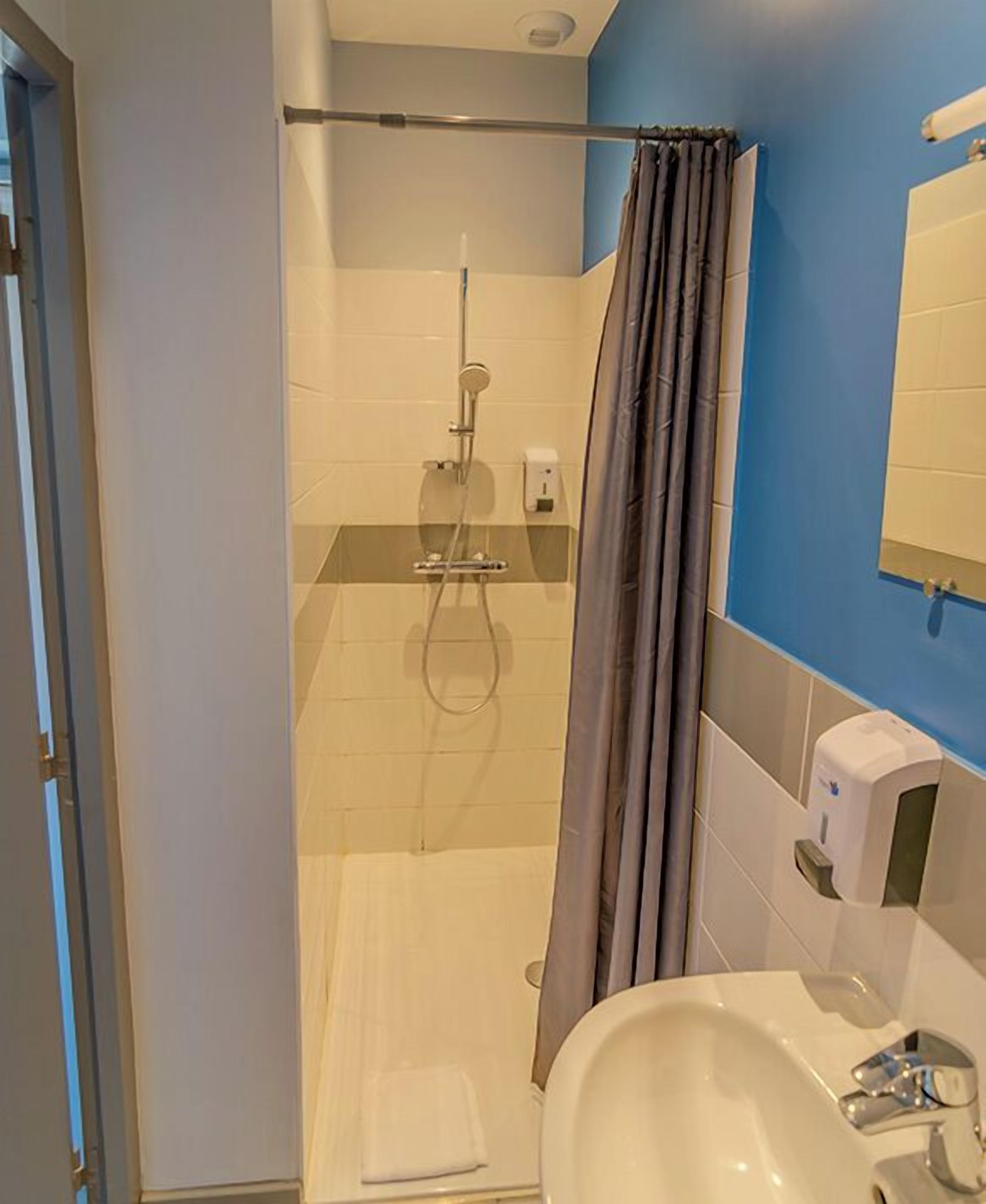 Un baño con ducha, lavabo y espejo.