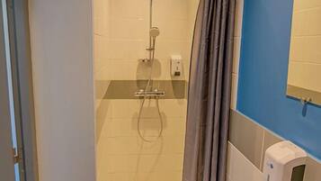 Une salle de bain avec une douche, un lavabo et un miroir.