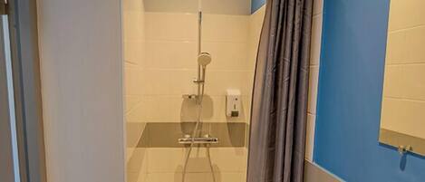 Un baño con ducha, lavabo y espejo.