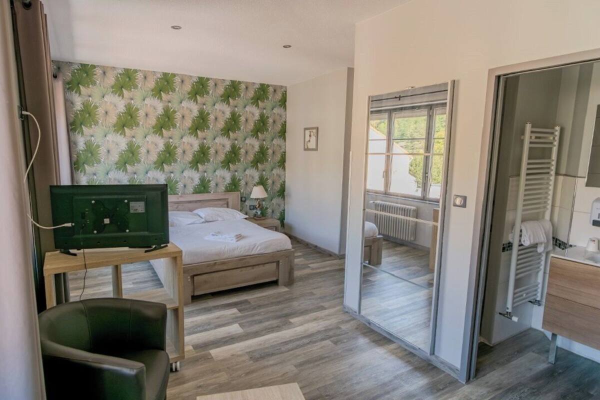 Een slaapkamer met een bed, een bureau, een stoel, een radiator en een badkamer met een handdoekrek.