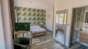 Een slaapkamer met een bed, een bureau, een stoel, een radiator en een badkamer met een handdoekrek.