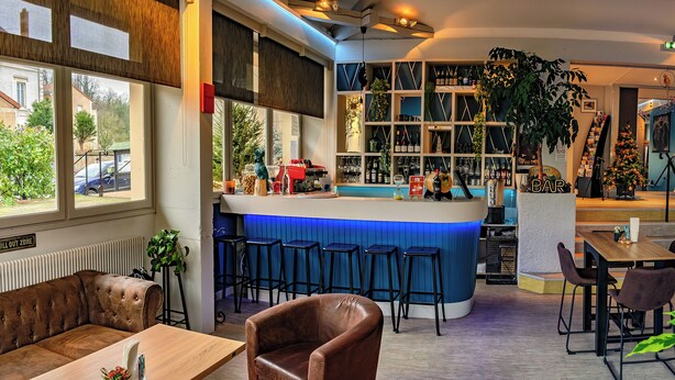 Zona de bar con taburetes, una barra y un árbol de Navidad.