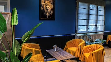 A room with a dark blue wall, a framed picture of a lion, and yellow-covered furniture.