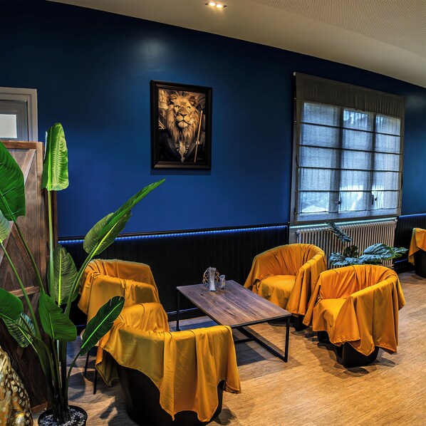 A room with a dark blue wall, a framed picture of a lion, and yellow-covered furniture. - Hôtel de l'Abbaye (Cluny)