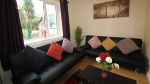 A living room with a black sofa, a coffee table, and a painting on the wall. - Keswick House Chesterfield (Chesterfield)