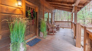 Une cabane en bois avec un porche, une porte ornée d’une guirlande et des sièges à l’extérieur.