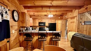 Un intérieur en bois comprenant un coin cuisine, une table à manger avec des chaises et un canapé.