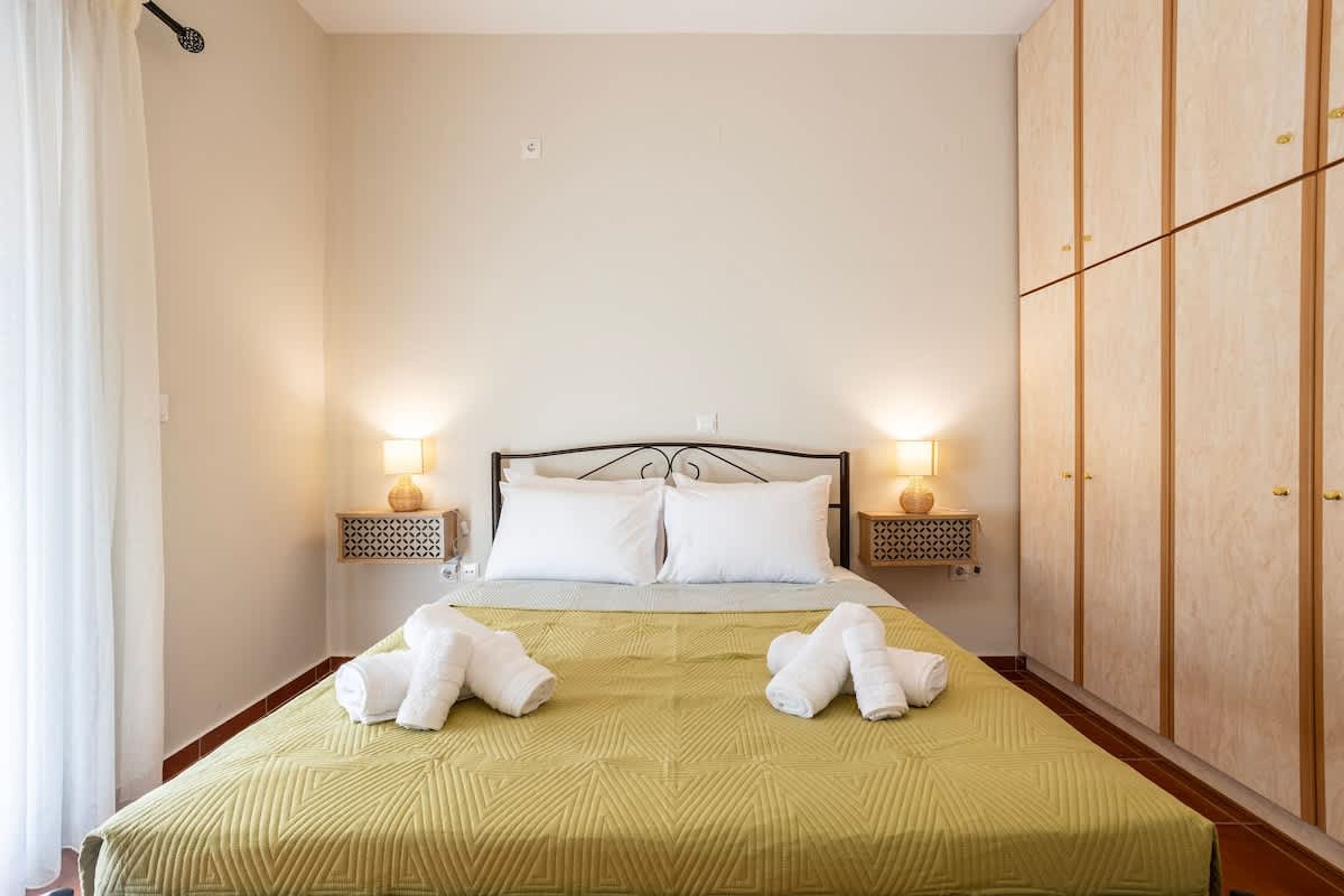 Ett hotellrum med en säng, två sänglampor, en garderob och handdukar på sängen.
